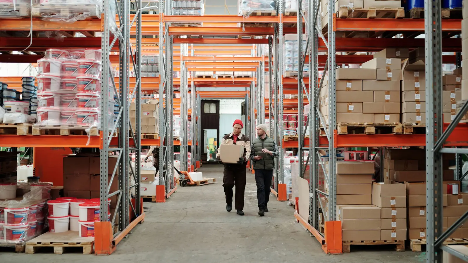 Warehouse workers moving boxes between storage shelves