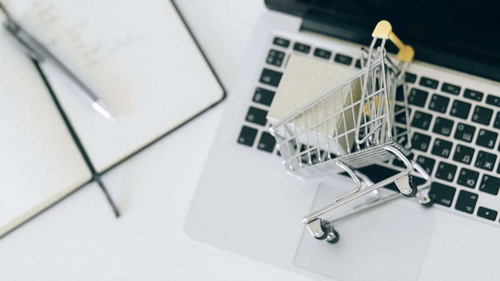 A miniature shopping trolley resting on a laptop keyboard