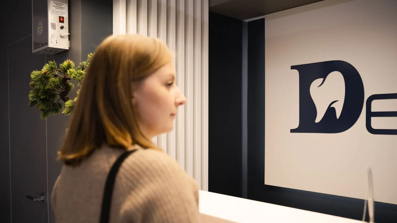 A patient standing at a dental clinic reception desk