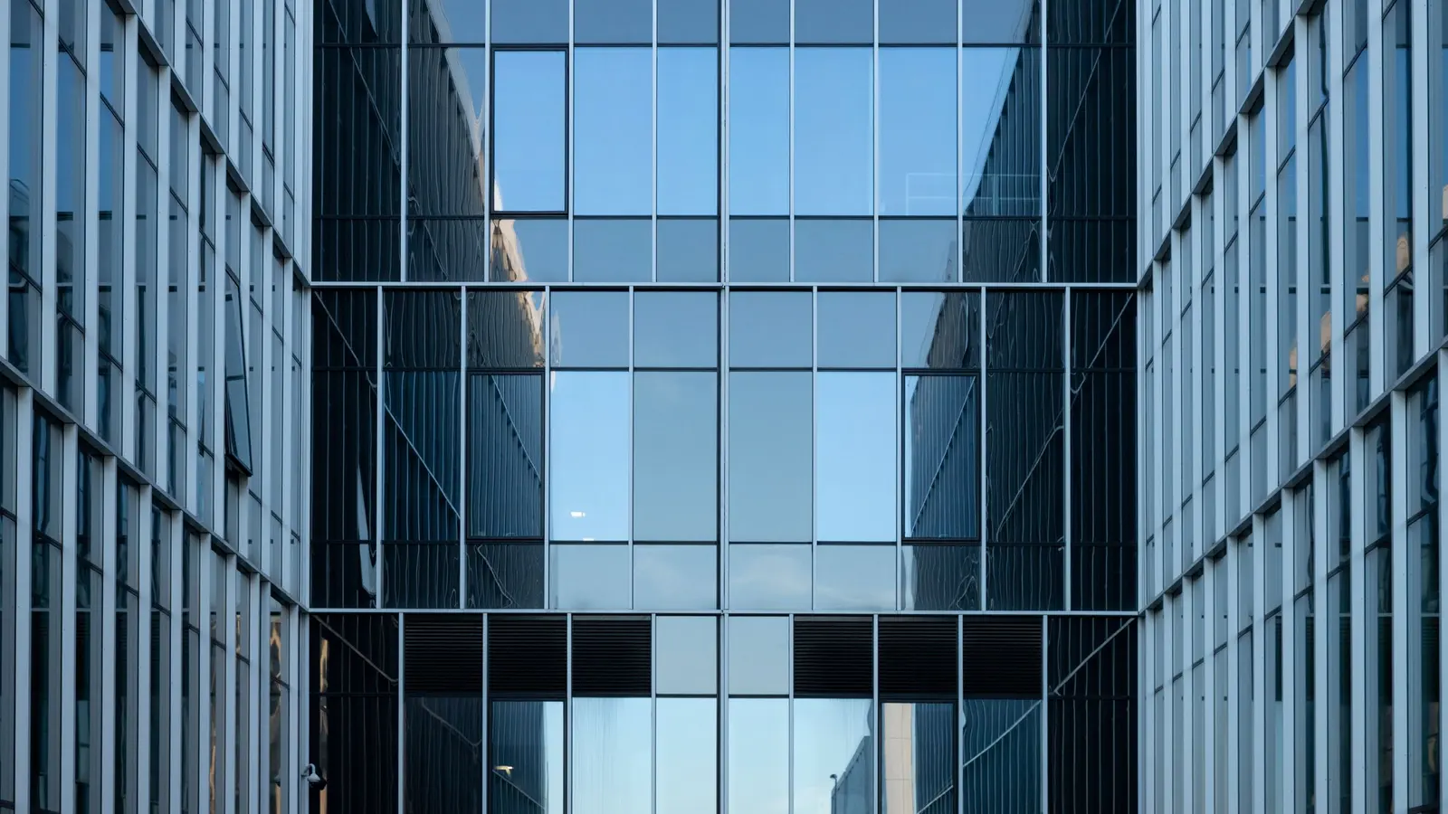 The glass facade of a corporate office building reflecting the sky