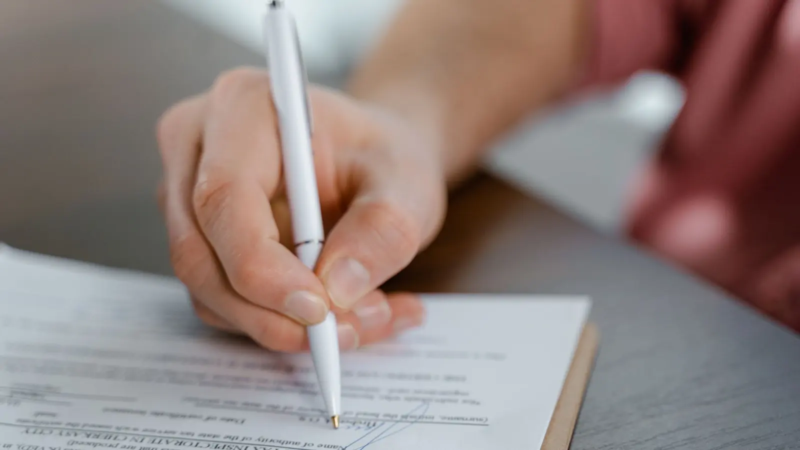 A person signing a contract with a ballpoint pen