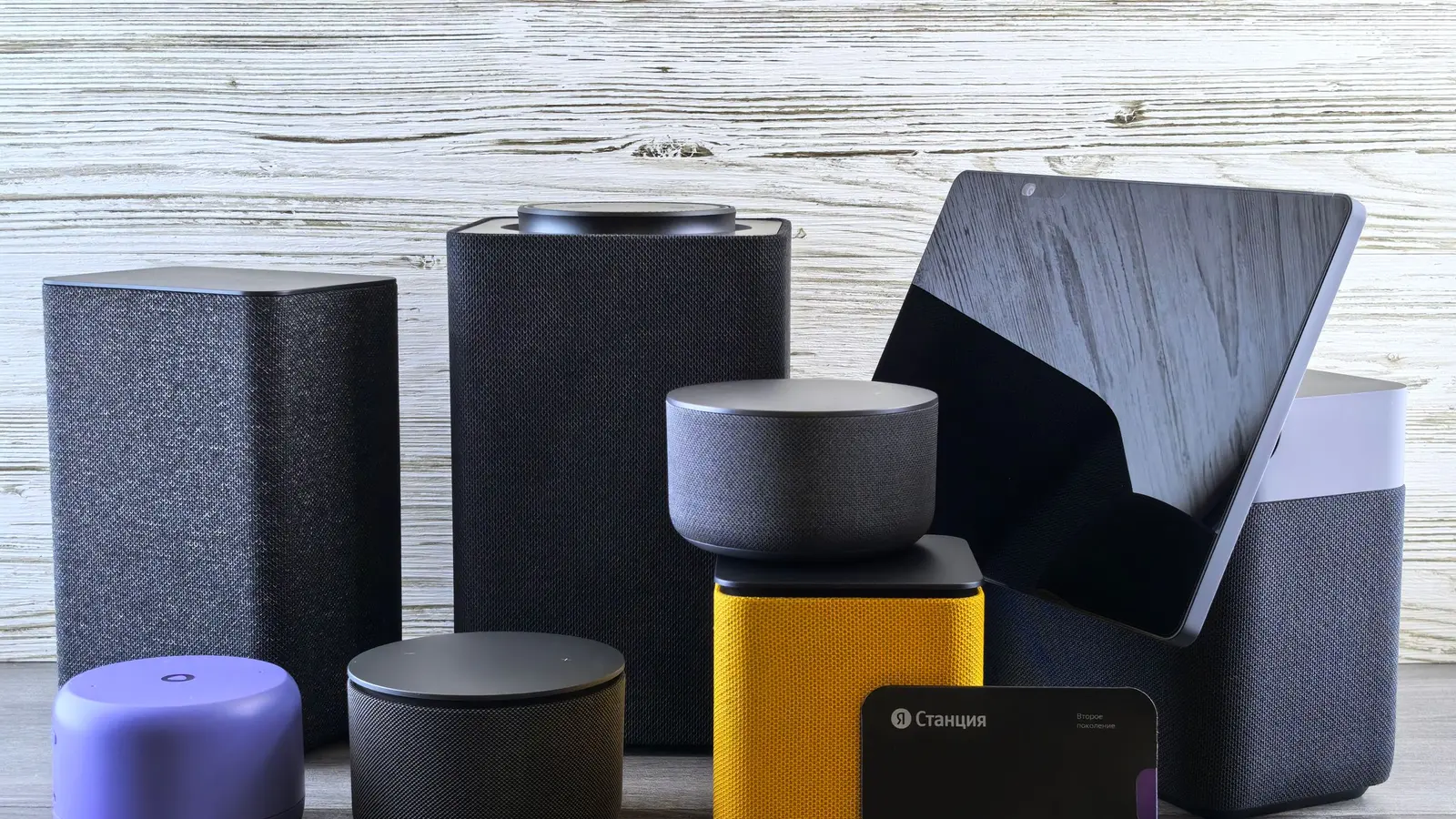 A collection of smart speakers and a tablet on a wooden surface