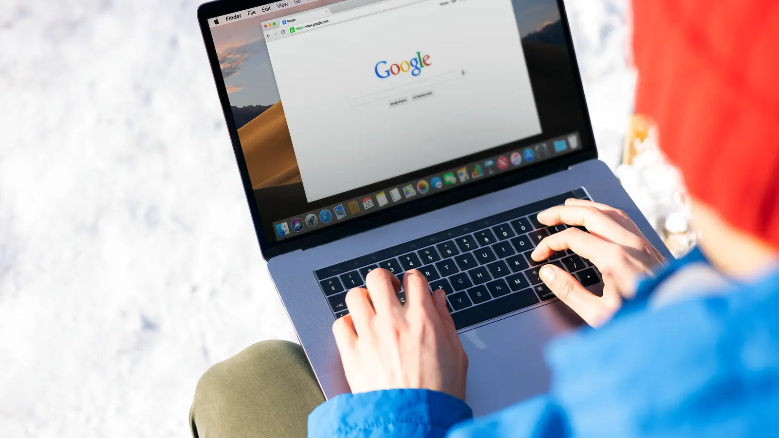 A person typing a search into Google on a laptop