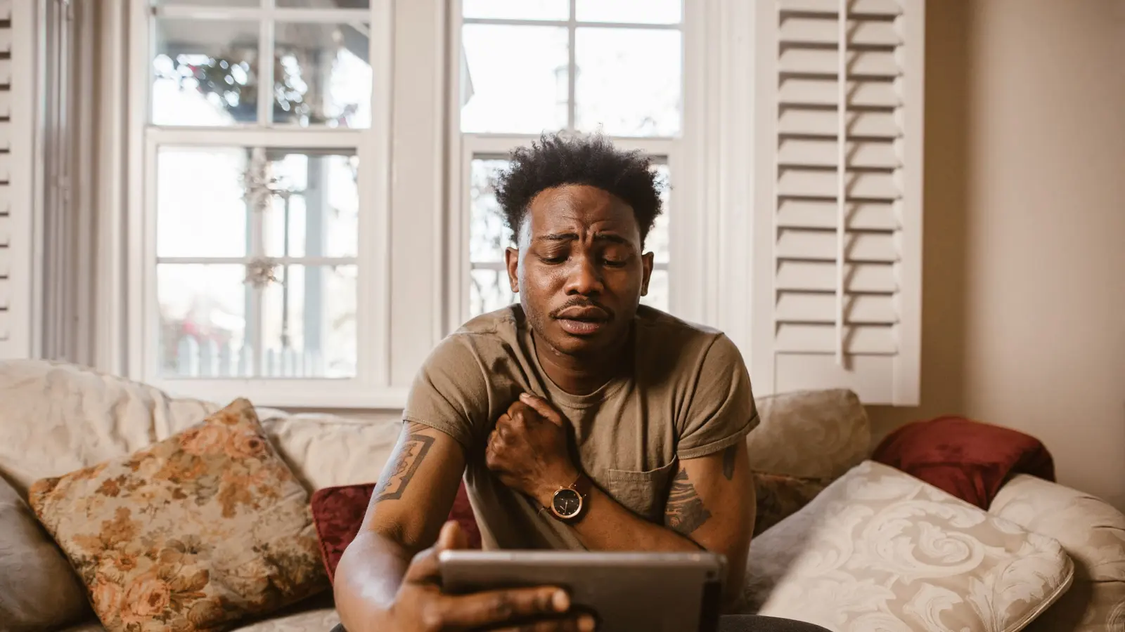 A man sitting on a couch watching a video on a tablet