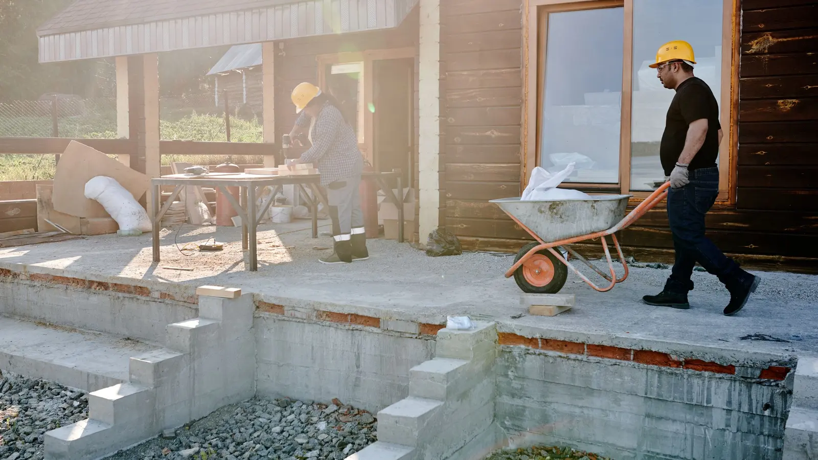 Two tradespeople working on the exterior of a house renovation