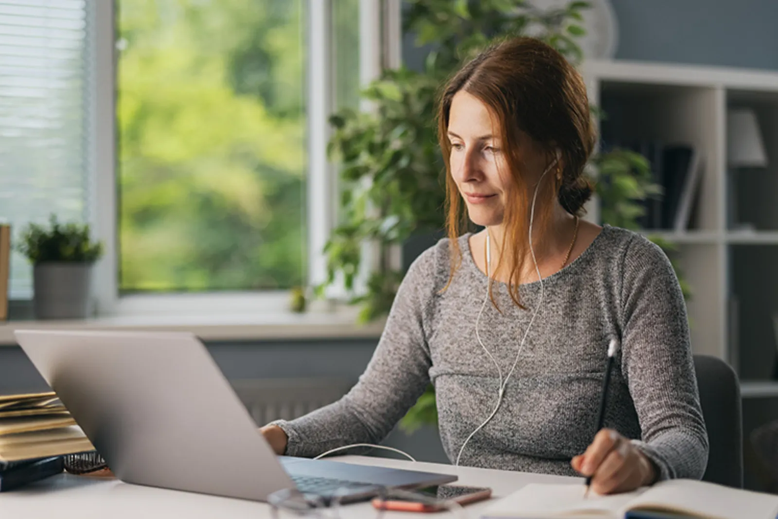 Woman with earphones studying an online course at a laptop