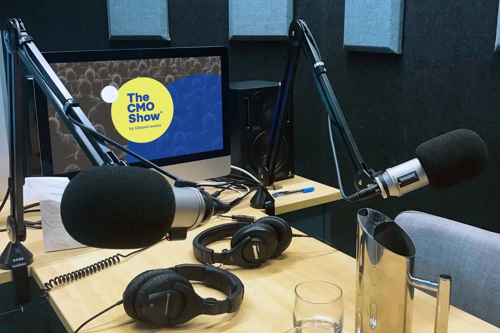 The CMO Show podcast studio with microphones, headphones and the show’s branding on screen